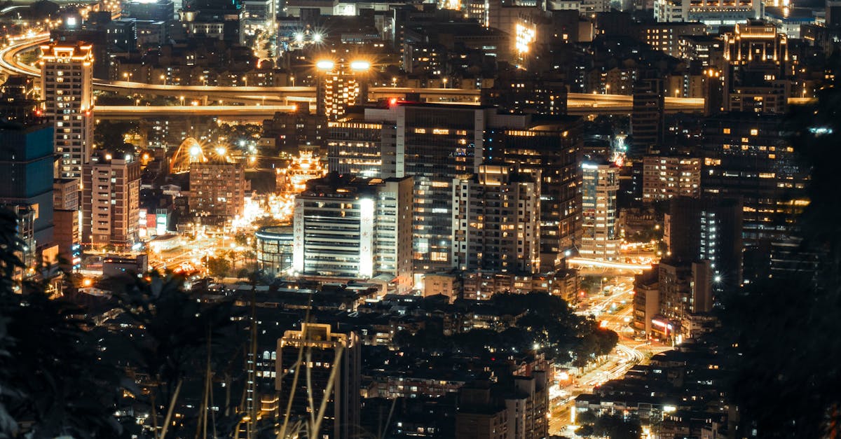 A vibrant city skyline at night with illuminated skyscrapers and bustling streets captured from above.